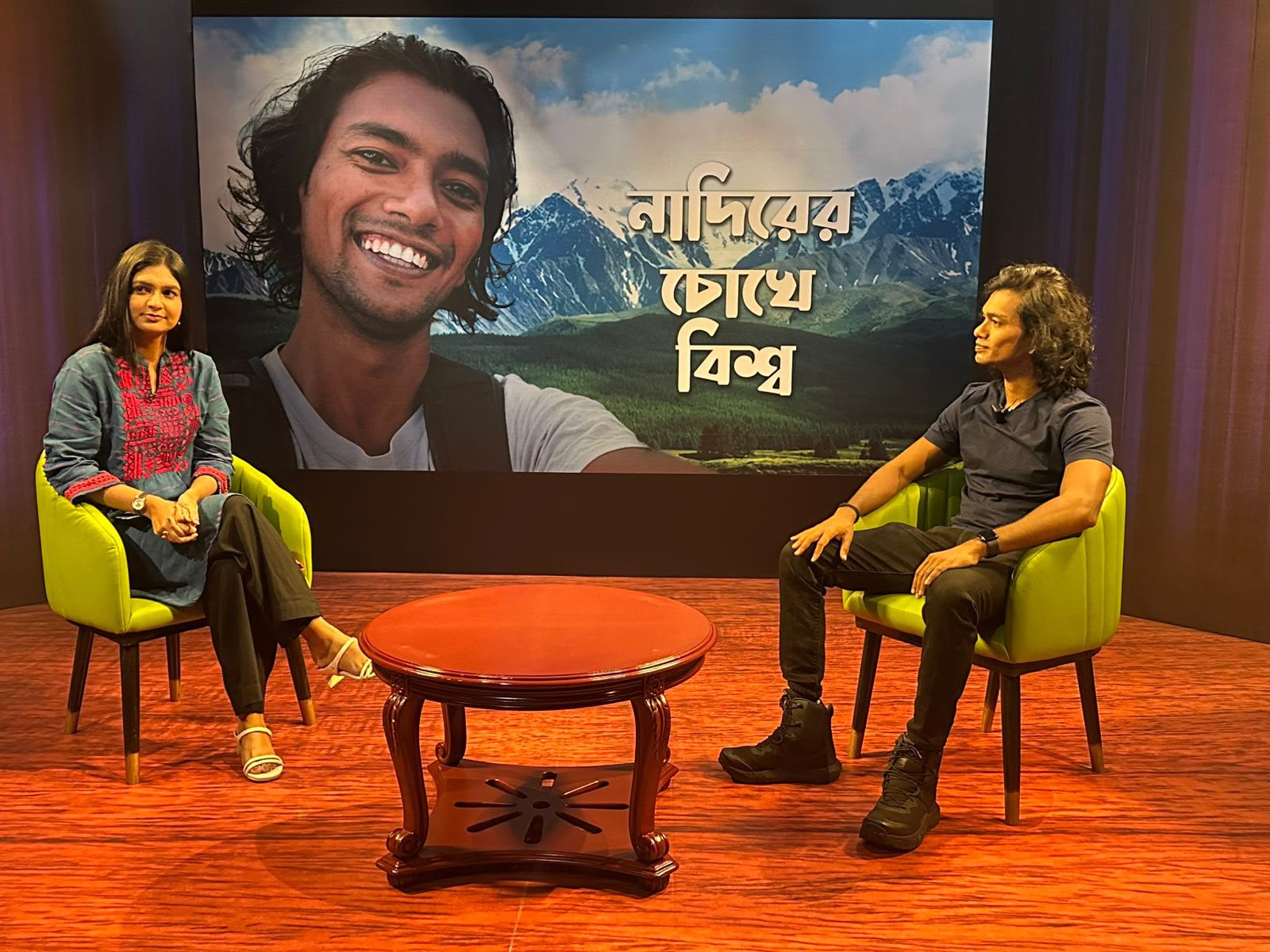 Sanjida Rahman interviewing a guest in front of a large studio screen at Channel i