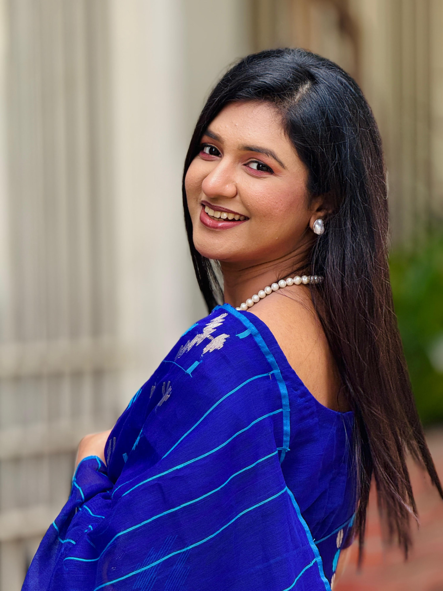 Studio portrait of Sanjida Rahman in a blue saree smiling over her shoulder