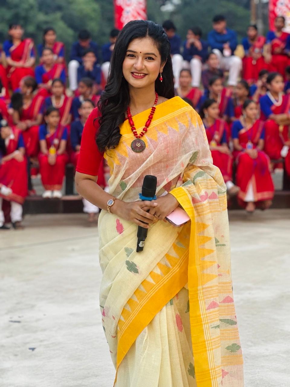 Sanjida Rahman hosting an outdoor school programme with students in uniform behind her