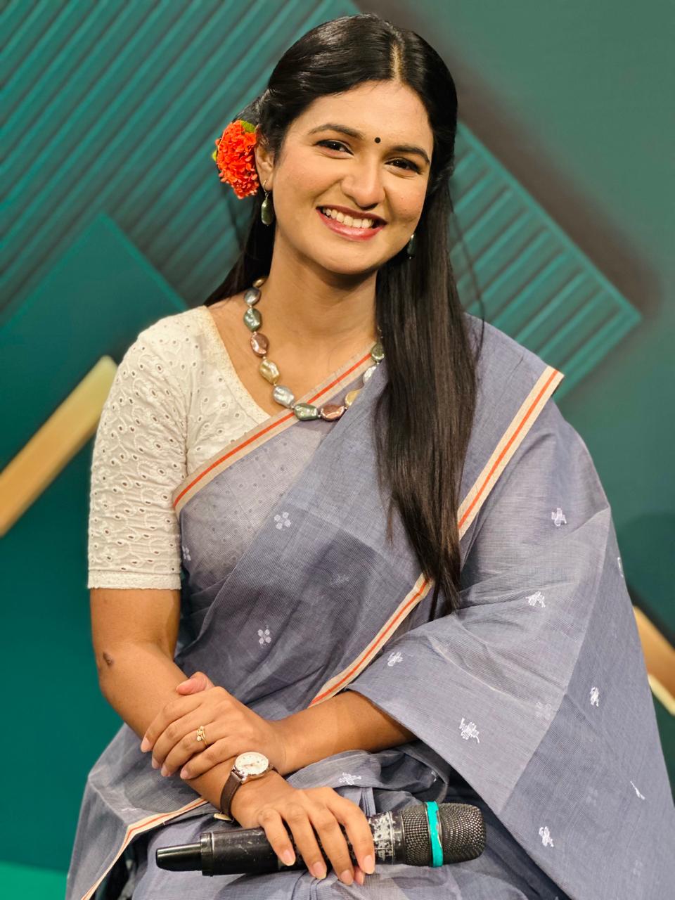 Close-up of Sanjida Rahman smiling with a microphone in hand on set